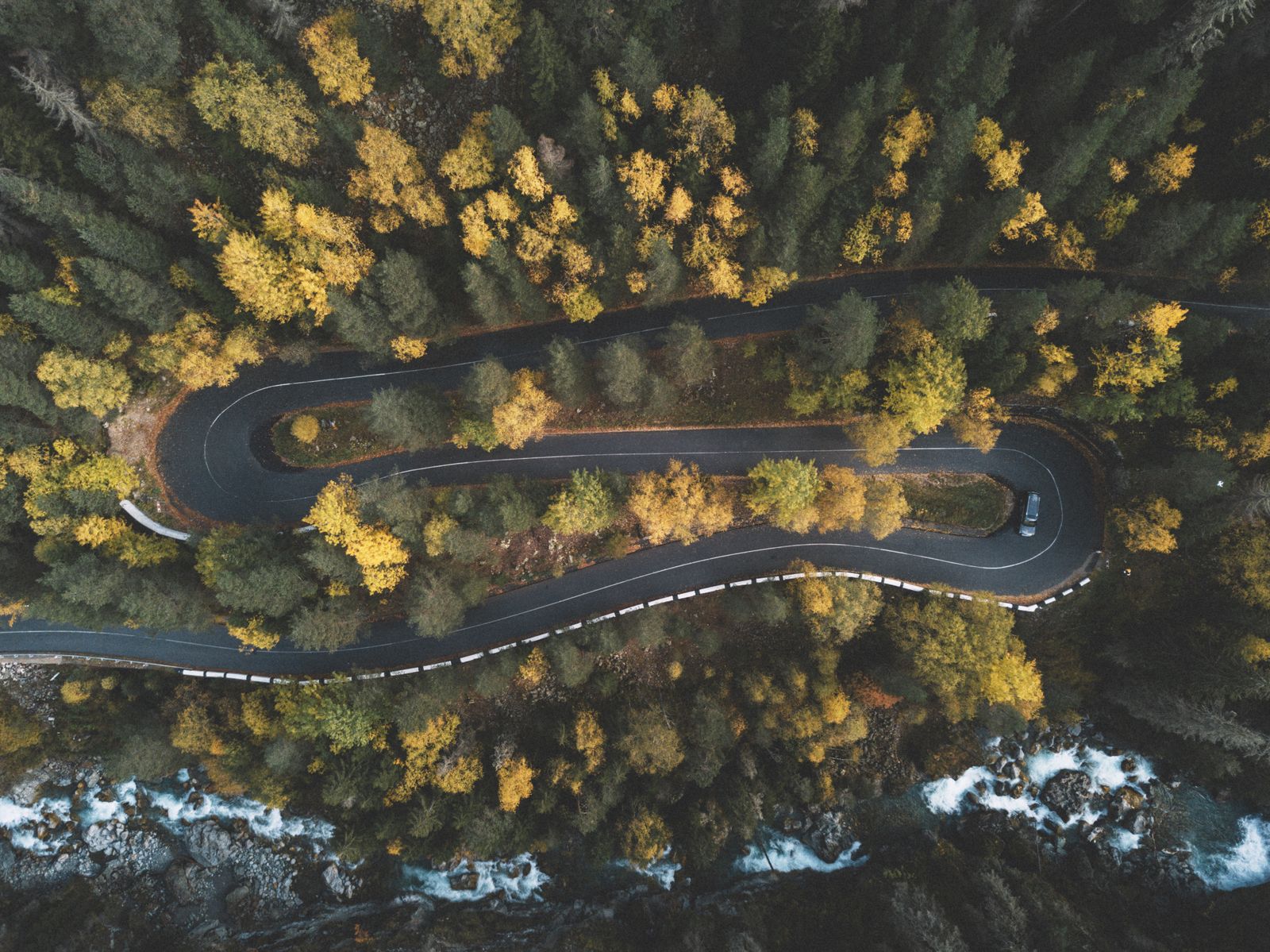 Aerial view of a curved road through autumn forest